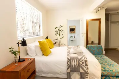 a bedroom with a bed and a chair and a window at Staymore in Stellenbosch