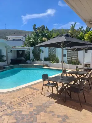 a pool with two tables and an umbrella at Thyme Wellness Spa and Guesthouse in Cape Town