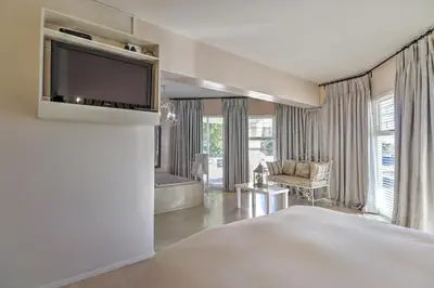 a hotel room with a bed and a television at Thyme Wellness Spa and Guesthouse in Cape Town
