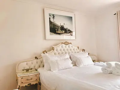 a white bed with white pillows and a picture on the wall at Princess Holiday Home in Cape Town