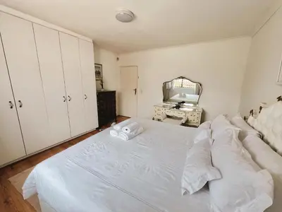 a white bed in a room with a mirror at Princess Holiday Home in Cape Town