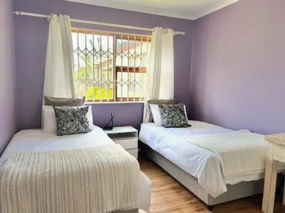 two beds in a room with purple walls and a window at Princess Holiday Home in Cape Town