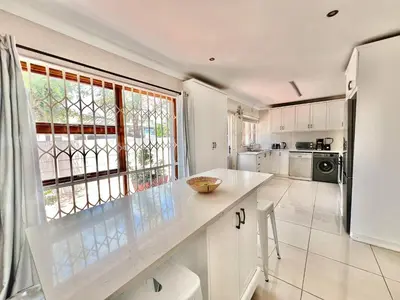 a kitchen with white cabinets and a large window at Princess Holiday Home in Cape Town