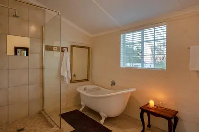 a bathroom with a tub and a glass shower at Honeyrock Cottages in Kleinmond