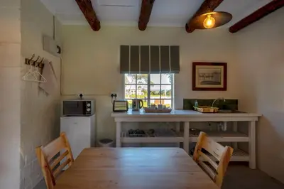 a kitchen with a wooden table and a refrigerator at Honeyrock Cottages in Kleinmond