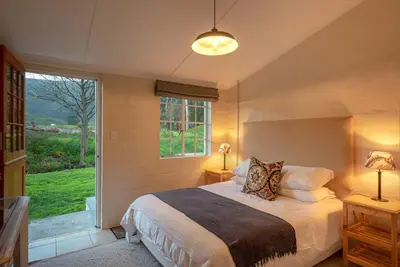 a bedroom with a bed and a large window at Honeyrock Cottages in Kleinmond