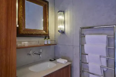 a bathroom with a sink and a mirror and towels at Blaauwklippen Manor by NEWMARK in Stellenbosch