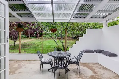 a patio with a table and chairs and a window at 4 ON REGENT in Greyton