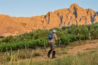 a man with a backpack walking down a dirt road at Vredehoek Guest Farm in Breerivier