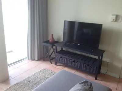 a living room with a flat screen tv on a stand at Sunset 786 Holidays 211 in Strand