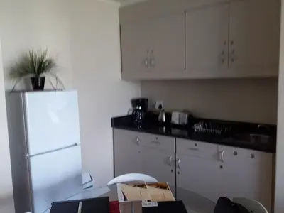 a kitchen with white cabinets and a white refrigerator at Sunset 786 Holidays 211 in Strand