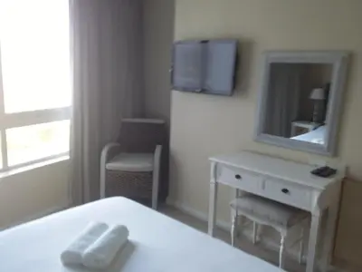 a room with a bed and a dresser and a mirror at Sunset 786 Holidays 211 in Strand