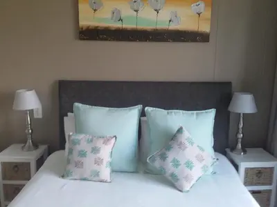 a bed with pillows and a painting on the wall at Sunset 786 Holidays 211 in Strand