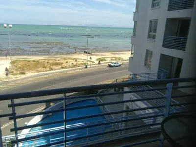 a balcony with a view of a beach and a building at Sunset 786 Holidays 211 in Strand
