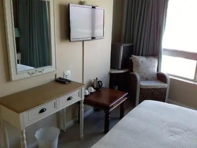 a hotel room with a bed and a desk and a television at Sunset 786 Holiday Accom-212 in Strand