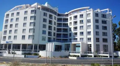 a large white building next to a street at Sunset 786 Holiday Accom-212 in Strand