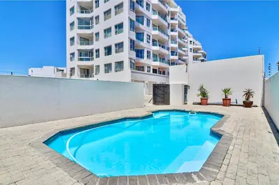 a swimming pool in front of a tall building at 603 Nautica in Cape Town