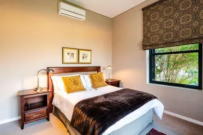 a bedroom with a bed with yellow pillows and a window at Farm Stay Winelands in Paarl