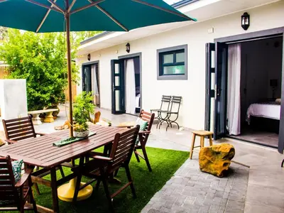 a patio with a wooden table with chairs and an umbrella at The Noble Lodge in Cape Town