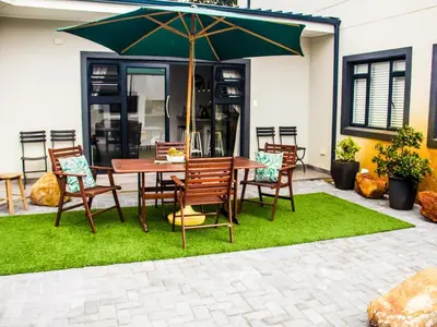 a patio with a table and chairs with an umbrella at The Noble Lodge in Cape Town
