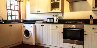 a kitchen with white cabinets and a washer and dryer at Navarre Farm Cottages in Stellenbosch