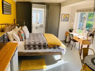 a bedroom with a bed and a table and a desk at Modern studio apartment in Cape Town