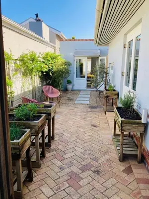 a patio with benches and potted plants on a house at Modern studio apartment in Cape Town