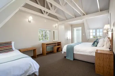 two beds in a room with white walls at Quainton Cottages in Hermanus