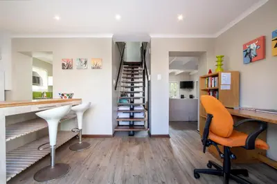 a room with a staircase and a desk and a chair at Quainton Cottages in Hermanus
