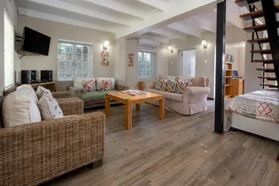 a living room with couches and a table at Quainton Cottages in Hermanus