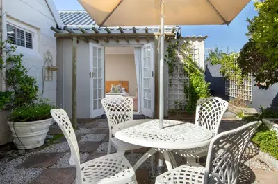 a table and chairs with an umbrella on a patio at Quainton Cottages in Hermanus