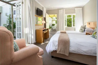 a large bedroom with two beds and a chair at Quainton Cottages in Hermanus