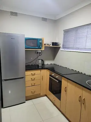 a kitchen with a stainless steel refrigerator and wooden cabinets at MO MAJOR in Cape Town