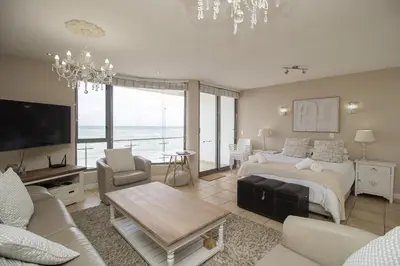 a bedroom with a bed and a living room at Hibernian Towers 402 Self Catering Accommodation Strand Western Cape South Africa in Cape Town
