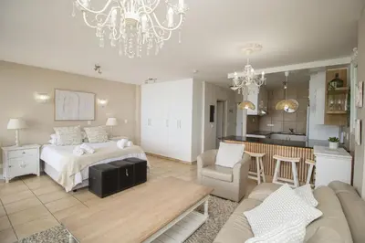 a bedroom with a bed and a living room at Hibernian Towers 402 Self Catering Accommodation Strand Western Cape South Africa in Cape Town