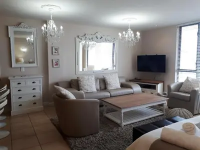 a living room with a couch and a table at Hibernian Towers 402 Self Catering Accommodation Strand Western Cape South Africa in Cape Town