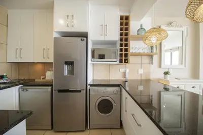 a kitchen with a refrigerator and a washing machine at Hibernian Towers 402 Self Catering Accommodation Strand Western Cape South Africa in Cape Town