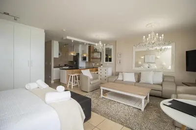 a living room with a bed and a couch and a kitchen at Hibernian Towers 402 Self Catering Accommodation Strand Western Cape South Africa in Cape Town