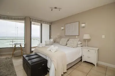 a bedroom with a bed with a view of the ocean at Hibernian Towers 402 Self Catering Accommodation Strand Western Cape South Africa in Cape Town