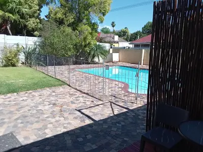 a fence around a swimming pool in a yard at 10 on Fairview B&B in Paarl
