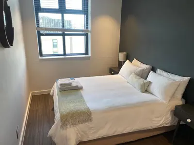 a bedroom with a large white bed with a window at Six One Five at Matrix in Cape Town