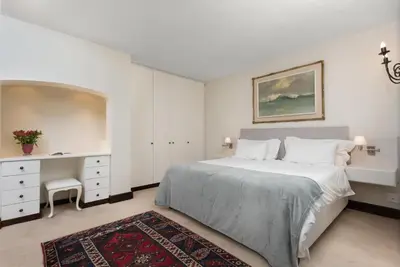 a white bedroom with a bed and a desk at 4 Piet Retief in Stellenbosch
