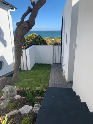 a stairway leading to a white building with a tree at Bungalow by the sea near Cape Town in Kleinmond