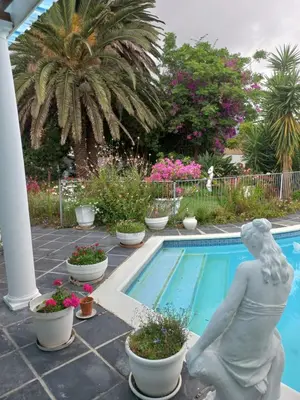 a statue of a woman sitting next to a swimming pool at Canberra on Greenwood in Cape Town