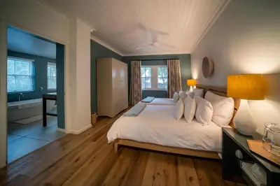 a bedroom with a large white bed and a bathroom at Heron House at Bartholomeus Klip in Hermon