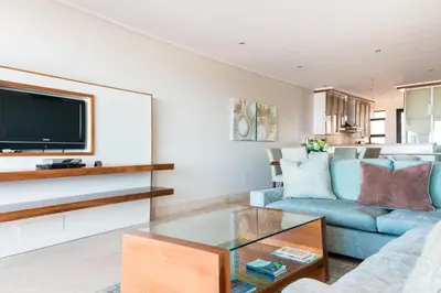 a living room with a blue couch and a tv at 74 on Marine in Hermanus