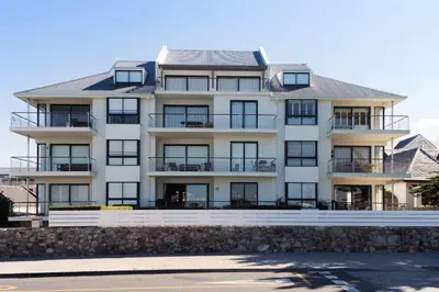 a large white apartment building with a stone wall at 74 on Marine in Hermanus
