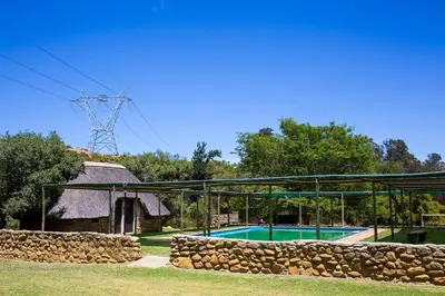a swimming pool with a stone wall next to a building at Steenbok farm cottages Aalwyn Cottage in Wolseley