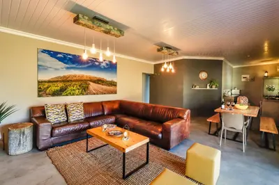 a living room with a leather couch and a table at Steenbok farm cottages Aalwyn Cottage in Wolseley
