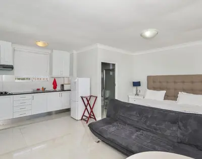 a living room with a couch and a kitchen at Ocean Way Villas - Self Catering in Cape Town